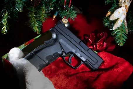 Black polymer handgun that is in a box under a Christmas tree