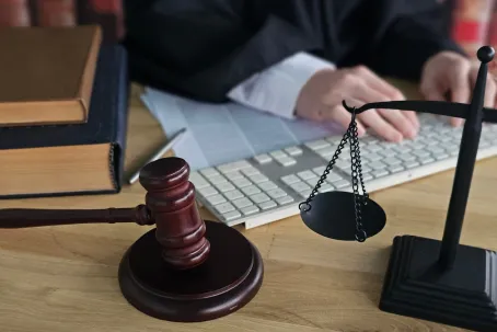 A judge prepares for a court hearing, using a gavel and scales on a table covered with law books