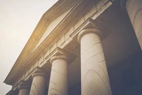 Close-up view of classical courthouse columns symbolizing law, justice, and authority.