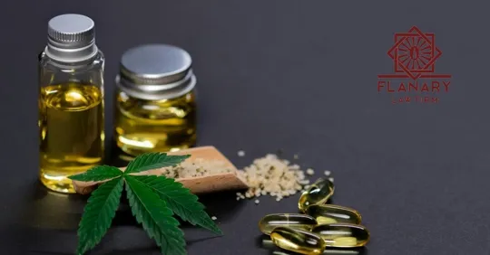 Cannabis products including marijuana oil bottles, capsules, and a cannabis leaf on a dark surface.