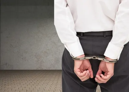An image of a man facing away with his hands handcuffed