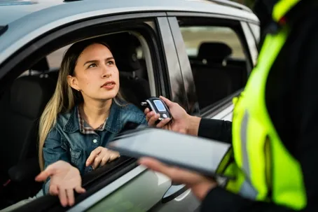 An image of a girl who is driving and stopped while a police officer is checking on her.